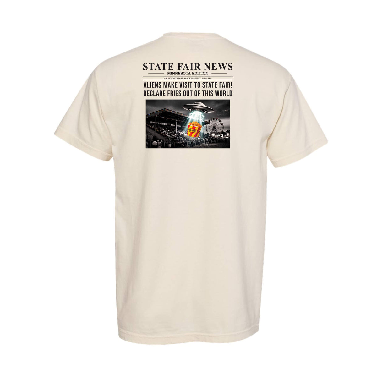 A cream-colored short-sleeve t-shirt shown from the back, featuring a graphic print styled like a newspaper headline that reads 'STATE FAIR NEWS' with a black-and-white photo of a fairground and a an alien spaceship sampling french fries.