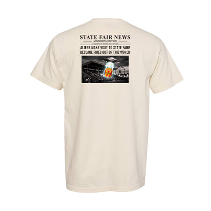 A cream-colored short-sleeve t-shirt shown from the back, featuring a graphic print styled like a newspaper headline that reads 'STATE FAIR NEWS' with a black-and-white photo of a fairground and a an alien spaceship sampling french fries.