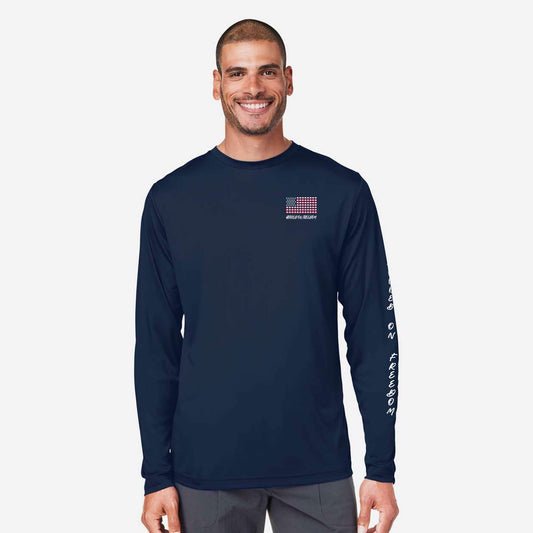 A man wearing a navy blue long-sleeve performance shirt with a small red, white, and blue American flag graphic on the left chest and white text down the right sleeve, set against a light gray background.
