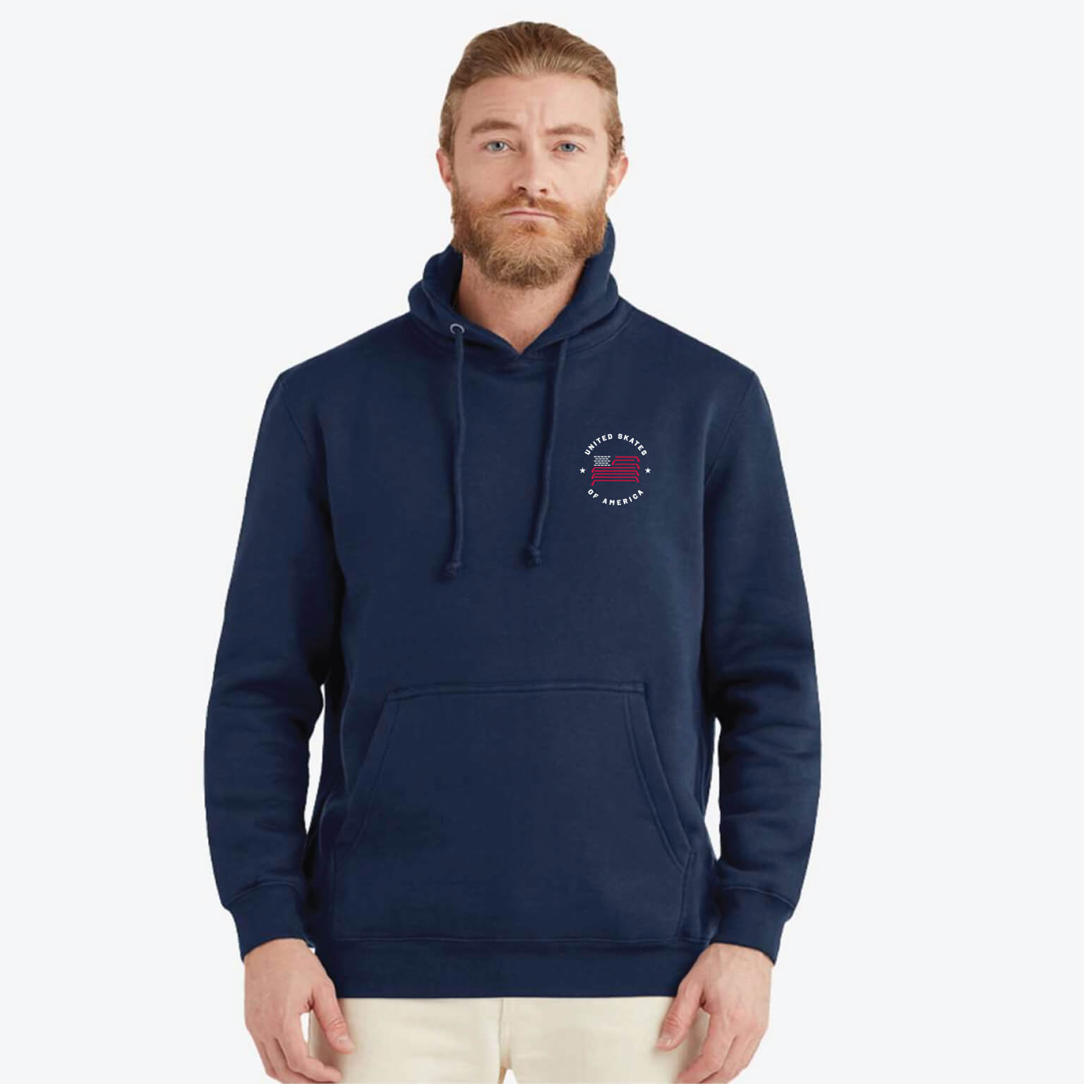 A man wearing a navy blue pullover hoodie with a small United Skates of America circular chest graphic, paired with light beige pants, photographed against a solid light gray background.